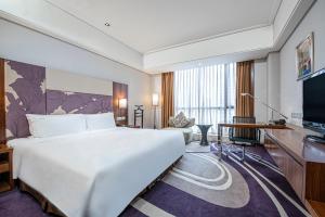 a hotel room with a large bed and a flat screen tv at Holiday Inn Qingdao City Center by IHG - May 4th Square in Qingdao +119 photos