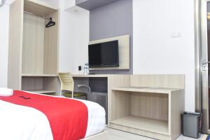 a bedroom with a bed and a tv on a wall at RedDoorz near Stasiun TVRI Surabaya 2 in Dukuhkupang