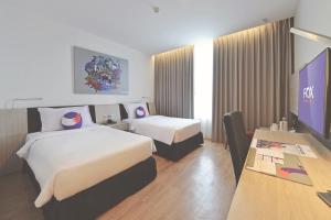 a hotel room with two beds and a flat screen tv at FOX Hotel Pekanbaru in Pekanbaru