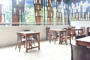 a dining room with tables and chairs and windows at RedDoorz near Stasiun TVRI Surabaya 2 in Dukuhkupang