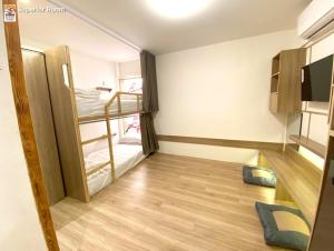 Pokój z 2 łóżkami piętrowymi i drewnianą podłogą w obiekcie โรงแรมชิบะรูม นครราชสีมา สาขามหาวิทยาลัยเทคโนโลยีสุรนารี w mieście Nakhon Ratchasima