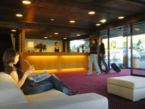 a woman sitting on a couch in a lobby at Wellnesshotel Linde in Sulzberg