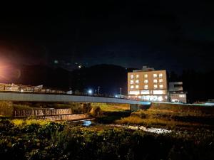 un puente sobre un río con un edificio por la noche en Hotel Omodaka, en Yamanouchi