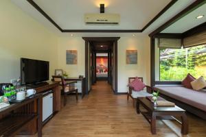a living room with a couch and a tv at The Village Resort & Spa - SHA Plus in Karon Beach