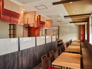a dining room with wooden tables and chairs at Henn na Hotel Komatsu Ekimae in Komatsu