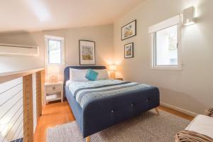a small bedroom with a blue bed and two windows at Allure Stradbroke Resort in Point Lookout