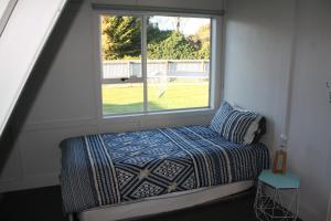 - une petite chambre avec un lit et une fenêtre dans l'établissement Classic A-frame on Milford, à Te Anau