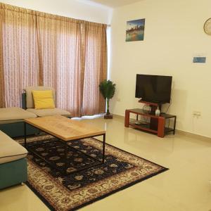 un soggiorno con divano e TV di Al Shumoo Apparment a Mascate