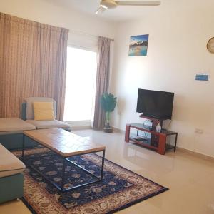 sala de estar con sofá y TV en Al Shumoo Apparment en Mascate