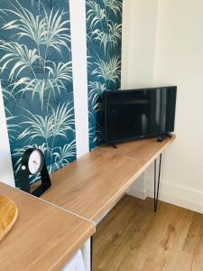 a desk with a television in a room with a wallpaper at le Nicole in Chartres