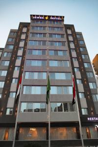 un grand bâtiment avec des drapeaux devant lui dans l'établissement Jewel Green Mountain Hotel, au Caire