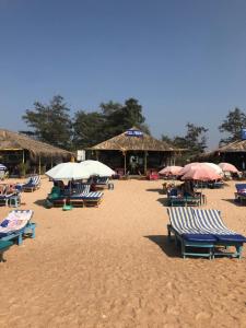 BardezにあるMaria guest houseのビーチに置かれた椅子とパラソルの群れ