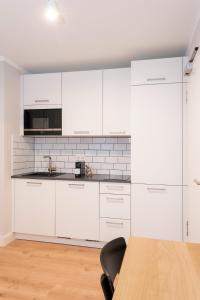 une cuisine avec des armoires blanches et une table en bois dans l'établissement The Woodmans Airport Boardinghouse, à Düsseldorf