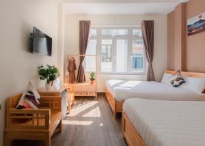 um quarto de hotel com duas camas e uma televisão em Moc Thach Hostel Dalat em Da Lat