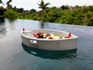 een kleine witte boot met voedsel in het water bij Yanyan Resort Ubud in Ubud