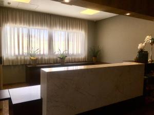 a lobby with a reception desk and a large window at Hotelog in Campina Grande do Sul