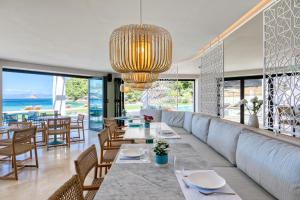 a restaurant with a long couch and tables and chairs at Vathi Cove Luxury Resort & Spa in Chrysi Ammoudia