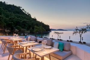 a restaurant with tables and chairs overlooking the water at Vathi Cove Luxury Resort & Spa in Chrysi Ammoudia