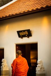 a monk in an orange robe standing in front of a building at Punyashthiti villa in Chanthaburi