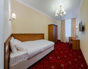 a hotel room with a bed and a red carpet at Отель МашБах in Cherepovets