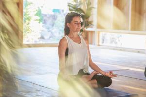 a woman sitting in a yoga pose in a room at Surfescape Fuerteventura in Lajares