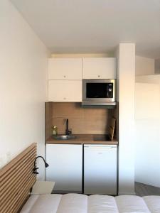 una pequeña cocina con fregadero y microondas en Bel appartement design tout confort (Parking Gratuit) à 10 minutes de Bordeaux, en Cenon