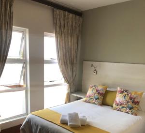 a bedroom with a bed with two pillows and two windows at 314 on Clark Guest House in Pretoria