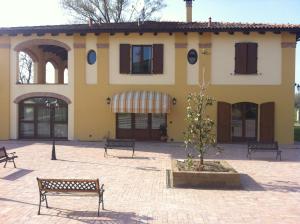 a building with benches and a tree in a courtyard at Antico Noce in Granarolo dellʼEmilia