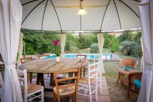 une table et des chaises sous une tente avec piscine dans l'établissement Mulino dei Camini, à Monteciccardo