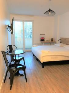 a bedroom with a bed and a table and chair at Bel appartement design tout confort (Parking Gratuit) à 10 minutes de Bordeaux in Cenon
