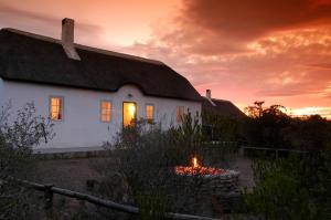 una casa bianca con un fuoco davanti al tramonto di De Hoop Collection - Vlei Cottages a De Hoop Nature Reserve