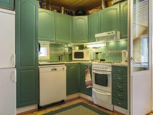 een groene keuken met witte apparaten en groene kasten bij Holiday Home Huuhkalinna by Interhome in Syöte