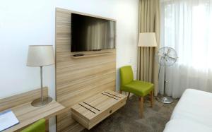 ein Hotelzimmer mit einem TV und einem grünen Stuhl in der Unterkunft Churchill hotel Terneuzen in Terneuzen