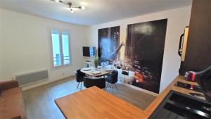 ein Wohnzimmer mit einem Tisch und einem großen Gemälde an der Wand in der Unterkunft Appartements Aux Portes d'Alès - Centre Ville in Alès