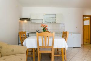 a kitchen with a table and chairs and a kitchen with white cabinets at Apartmani Luka in Kornić