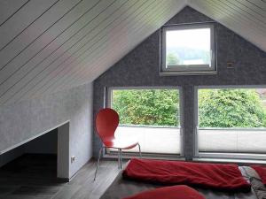 een slaapkamer met een rode stoel en een raam bij Casa Roja in Hilders