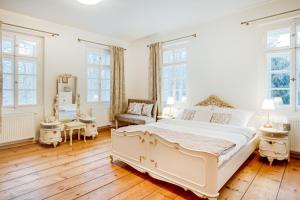 sypialnia z dużym białym łóżkiem i drewnianą podłogą w obiekcie Lovecký zámeček pod Milešovkou w Cieplicach