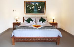 1 dormitorio con 1 cama grande y 2 lámparas en Green Coconut Cottage, en Ubud
