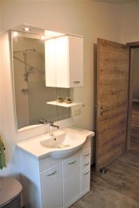 uma casa de banho com um lavatório, um espelho e uma porta em Apartments Traun-haft em Bad Aussee