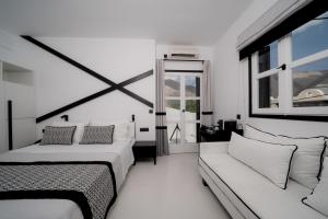 ein weißes Zimmer mit 2 Betten und einem Sofa in der Unterkunft Divelia Hotel in Perissa