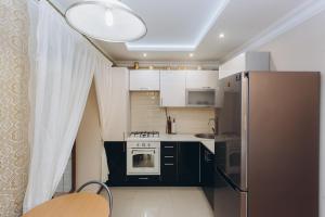 uma cozinha com armários a preto e branco e um frigorífico em Luxury Apartment em Sumy