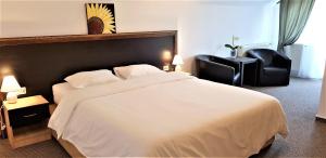 a bedroom with a large white bed and two black chairs at FOX VALLEY VILLA in Predeal