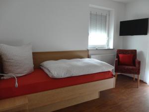 1 dormitorio con 1 cama, 1 silla y TV en Ferienwohnung 2 in den Krautgärten, en Zaberfeld