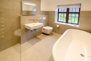 a bathroom with a tub and a sink and a toilet at Heron Place, Great Langdale in Ambleside