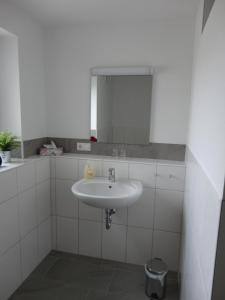 uma casa de banho branca com um lavatório e um espelho em Ferienwohnung 2 in den Krautgärten em Zaberfeld
