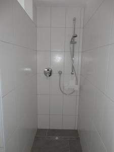 y baño de azulejos blancos con ducha. en Ferienwohnung 2 in den Krautgärten, en Zaberfeld