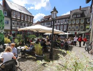 un grupo de personas sentadas en mesas en una calle con edificios en Fachwerk-Kultur-Pension TangoBrücke en Einbeck