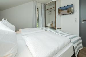 ein weißes Bett in einem Zimmer mit Fenster in der Unterkunft Upstalsboom Residenzen Trassenheide in Trassenheide