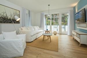 ein Wohnzimmer mit einer weißen Couch und einem Tisch in der Unterkunft Upstalsboom Residenzen Trassenheide in Trassenheide