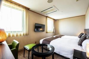 a hotel room with two beds and a tv at Hotel Quest Shimizu in Shizuoka